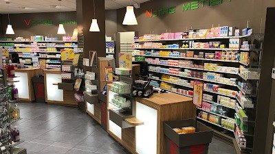 Pharmacie agencée : comptoirs bois et blanc, linéaires éclairés et suspensions